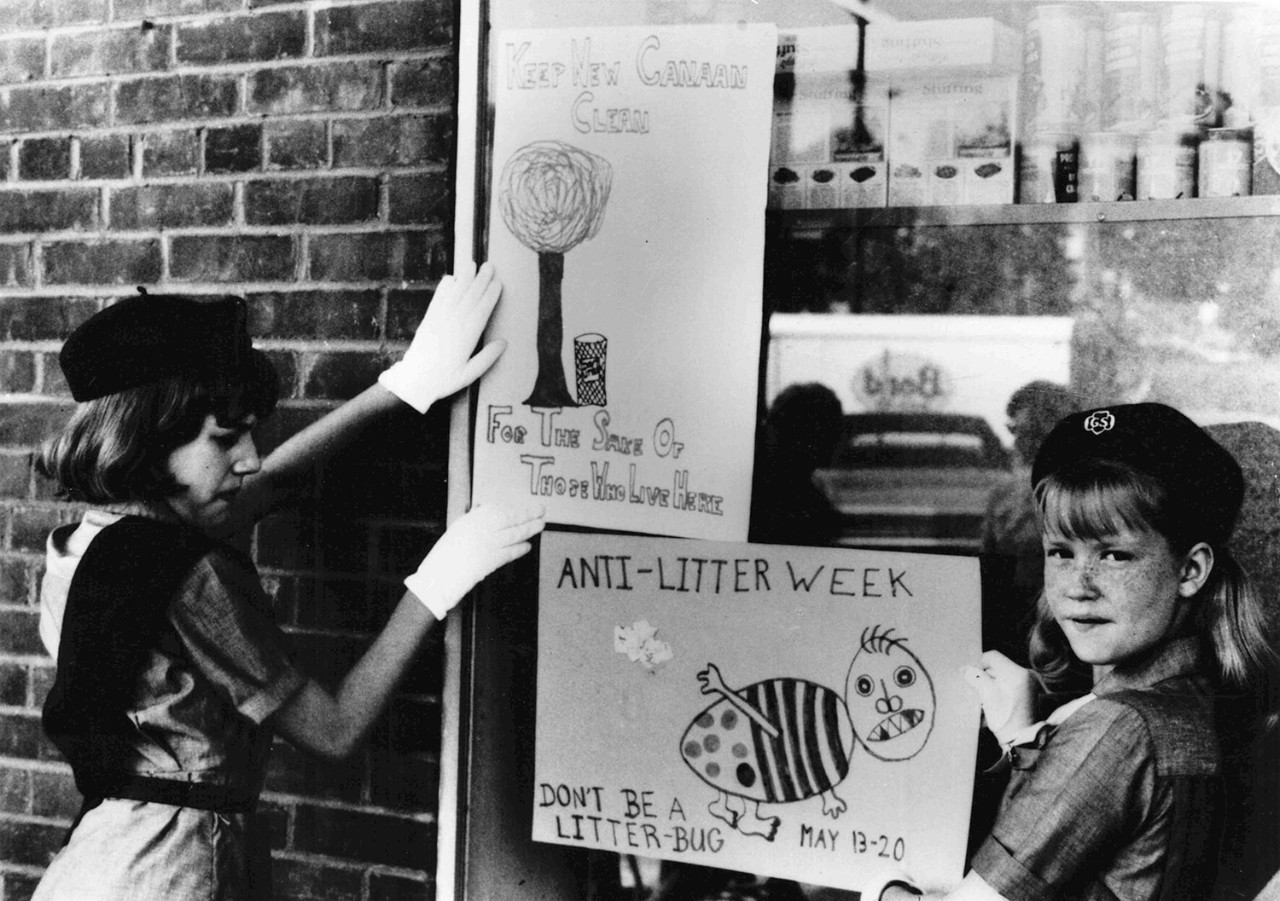 Girl Scouts hang anti-littering posters on shop window, 1976 