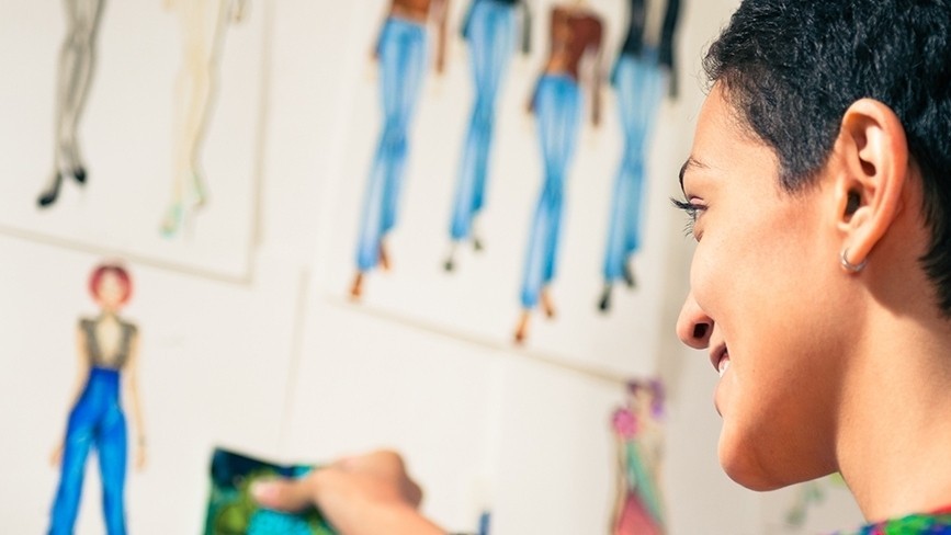 Female fashion designer contemplating drawings in studio