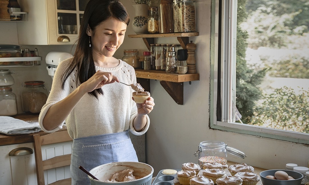 Woman adding chocolate frosting to cupcake food photography recipe idea