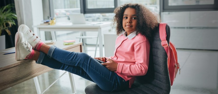 girl boss wearing jeans and a pink sweater in an office with her feet up on the desk