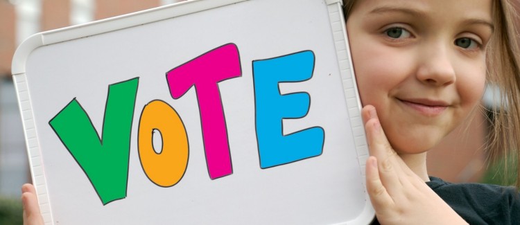 young girl holding a sign urging people to vote