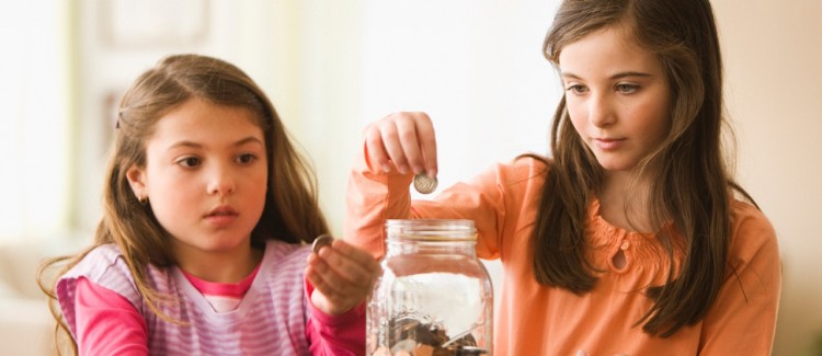 Girls saving coins in a jar learning about financial literacy