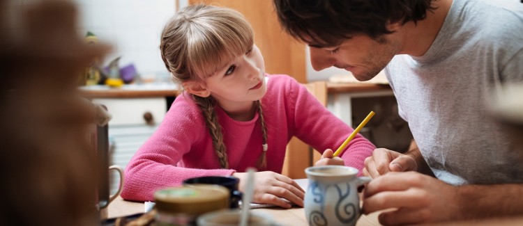 After school schedule: Young girl and her dad doing homework at the kitchen table