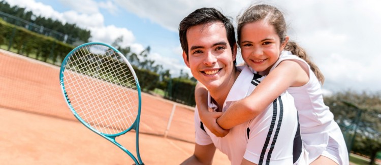 Healthy dad and young daughter on tennis court