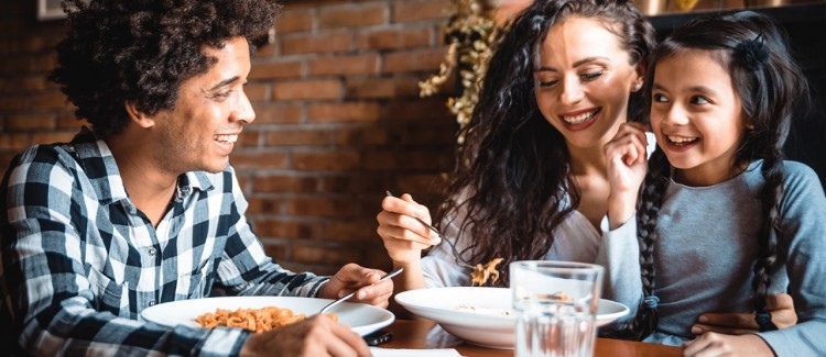 girl with her family having a fun conversation while eating pasta dinner