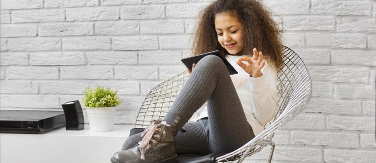 Girl sitting in chair on tablet learning how to be a digital leader