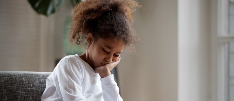 Girl in white shirt resting her head on her hand looking anxious and depressed