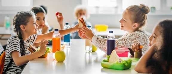 No parents in lunchroom, just girls eating sandwiches and fruit.