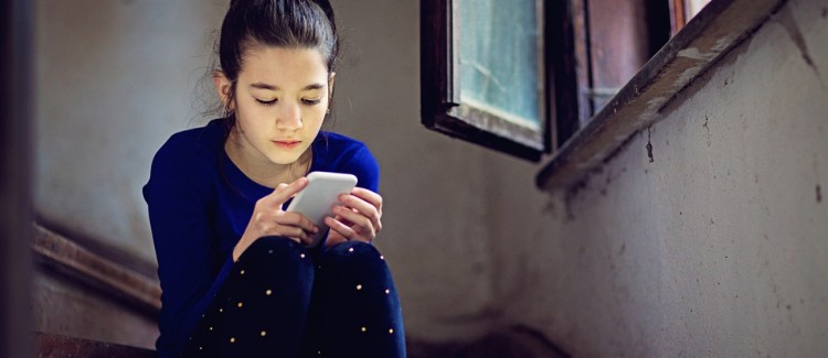 young girl on phone looking like she could be using an anonymous app like Saraha