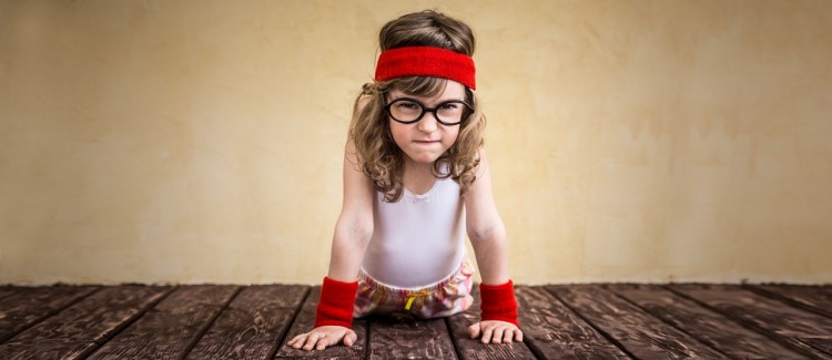 strong little girl doing a pushup on a wooden floor