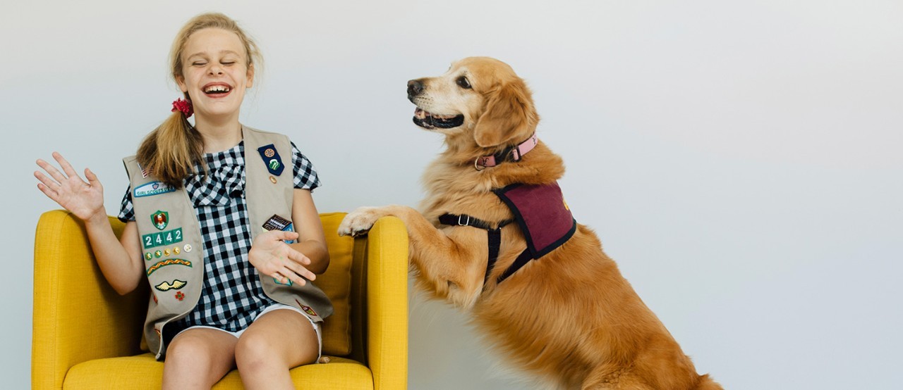 Girl Scout Cadette playing with a golden retriever